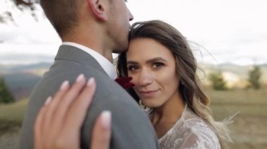 Genç ve güzel evliler gelin ve damat kucaklaşıyorlar, dağ yamacında sarılıyorlar, aşık düğün çifti