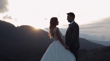 Yeni evliler, siluetler gelin, damat dağ yamacında sarılıyor, el ele tutuşuyor, düğün çifti ailesi