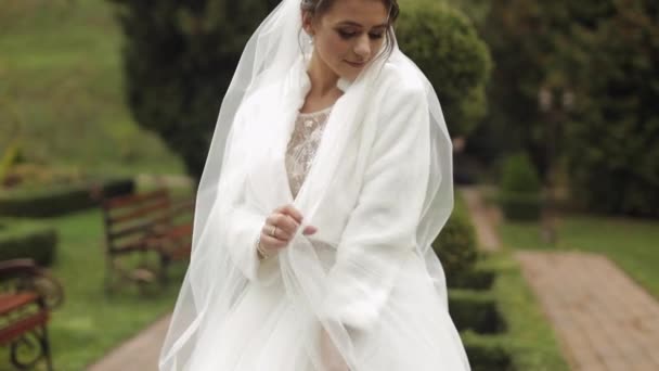 Gyönyörű és szép menyasszony esküvői ruha és fátyol a parkban várja a vőlegény. Lassú mozgás.