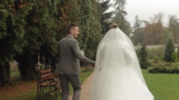 Bella sposi caucasici sposo correre nel parco, tenendosi per mano, matrimonio coppia famiglia — Video Stock