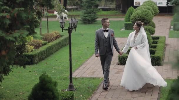 Mooi pasgetrouwde blanke bruid bruidegom wandelen in het park, hand in hand, huwelijk paar familie — Stockvideo