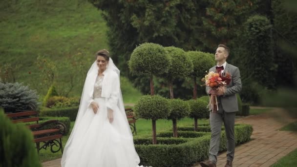 Preciosos recién casados caucásicos novia y novio con ramo en el parque, pareja de boda primera reunión — Vídeos de Stock