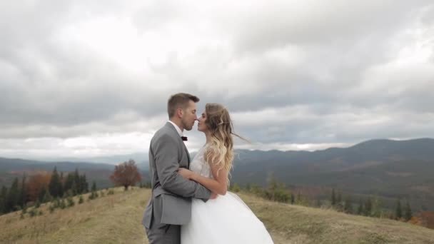 Όμορφη νύφη νεόνυμφοι γαμπρός αγκαλιάζει στην πλαγιά του βουνού, κρατώντας τα χέρια, γάμο ζευγάρι οικογένεια — Αρχείο Βίντεο