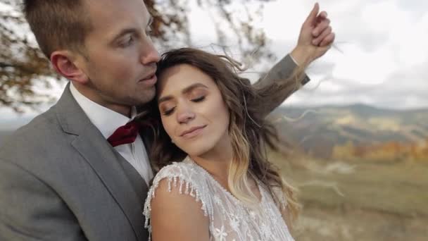 Genç ve güzel evliler gelin ve damat kucaklaşıyorlar, dağ yamacında sarılıyorlar, aşık düğün çifti — Stok video