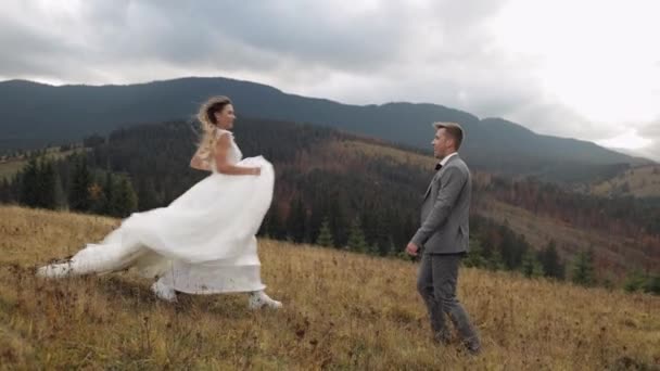 Schöne frisch vermählte Brautleute tanzen in Zeitlupe auf dem Berghang im Herbst, Hochzeitspaar Familie — Stockvideo