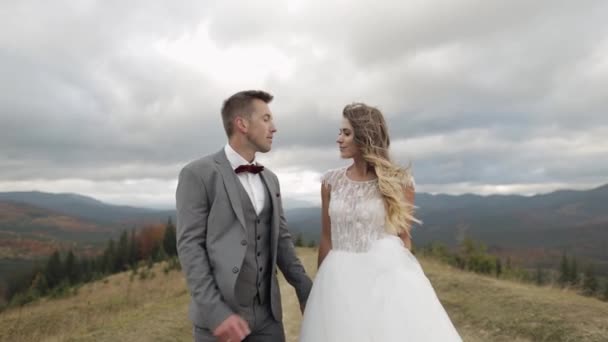 Precioso joven recién casados novio novia caminando en la ladera de la montaña, haciendo un beso, boda pareja familia — Vídeos de Stock