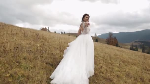 Mulher noiva recém-casada em casamento vestido elegante andando ou correndo na colina inclinação da montanha para noivo — Vídeo de Stock