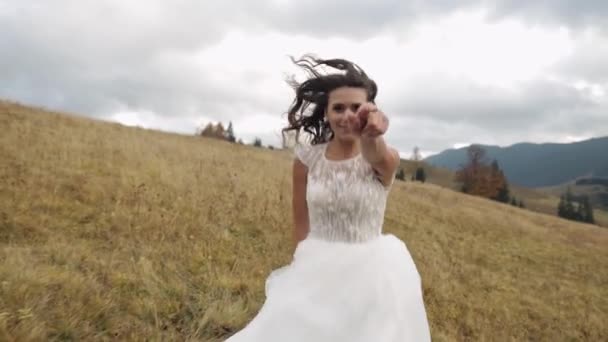 Novia mujer recién casada en vestido de novia elegante caminar o correr en la colina pendiente de la montaña para el novio — Vídeos de Stock