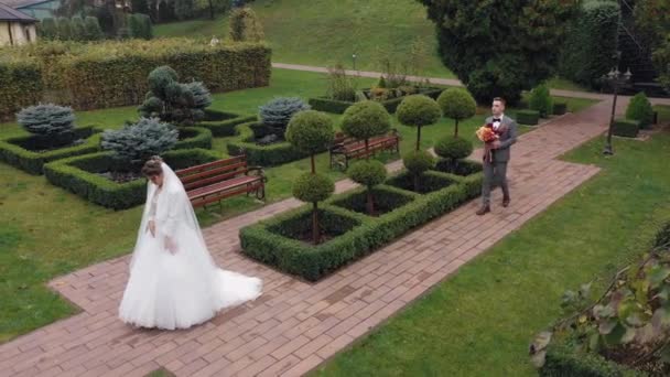 Pengantin baru mempelai wanita dan pria dengan buket di taman, pasangan pengantin pertama kali bertemu, pandangan drone udara — Stok Video