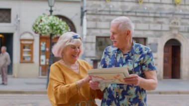 Büyük anne ve büyük baba turistler kağıt harita kullanarak yeni bir şehre gitmek için yer arıyorlar.