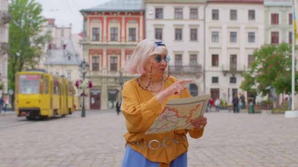 Senior snygg turist mormor kvinna promenader längs gatan, letar efter sätt att använda papperskarta i staden — Stockvideo