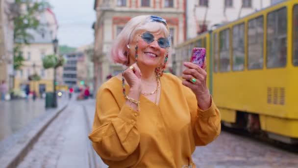 Seniortourist mit Retro-Fotokamera, lächelnd, Musik hörend, auf der Straße tanzend — Stockvideo