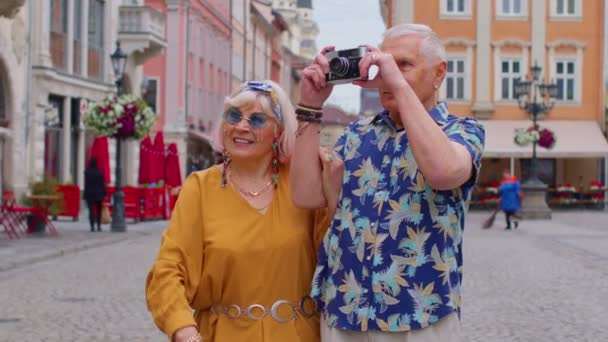 Äldre eleganta turister man och kvinna ta bilder med gamla film kamera, promenader längs stadens gata — Stockvideo