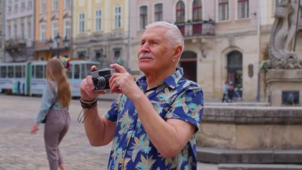 Старший турист фотографує з фотоапаратом в літньому центрі міста, життя після виходу на пенсію — стокове відео