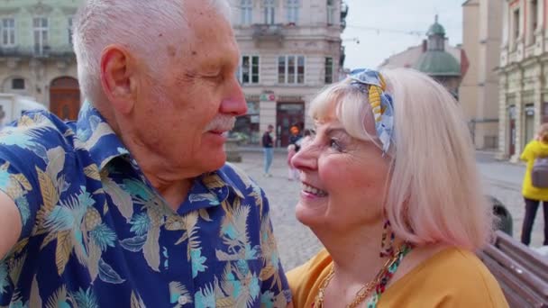 POV φωτογραφία των ηλικιωμένων τουριστών ζευγάρι λήψη selfie στο κέντρο της πόλης του καλοκαιριού χαμογελώντας, κοιτάζοντας κάμερα — Αρχείο Βίντεο