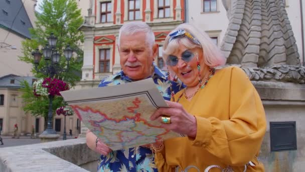 Senior γιαγιά και ο παππούς τουρίστες που ψάχνουν για ένα μέρος για να πάει στη νέα πόλη χρησιμοποιώντας χαρτί χάρτη — Αρχείο Βίντεο