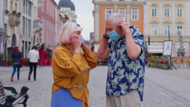 Yaşlı çift turistler, büyükanne ve büyükbaba tıbbi koruyucu koronavirüs maskesi takıyor. — Stok video