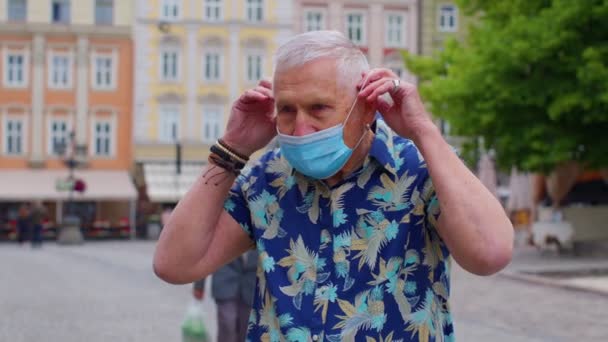 Covid-19 lockdown, sênior elegante turista homem avô vestindo máscara protetora na rua da cidade — Vídeo de Stock