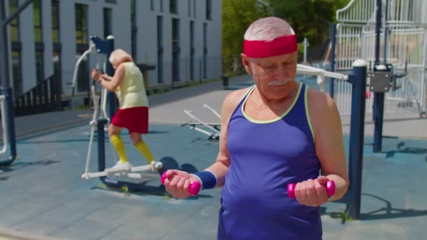 Hombre mayor abuelo haciendo ejercicio de levantamiento de pesas de entrenamiento activo con mancuerna en el patio de recreo — Vídeos de Stock