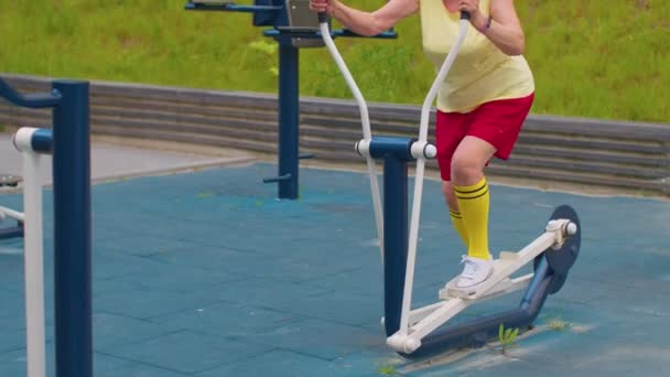 Mujer mayor abuelo de 70 años haciendo entrenamiento deportivo haciendo ejercicio en el patio de recreo orbitrek — Vídeos de Stock