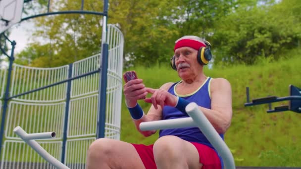 Senior kvinde efter sport træning lytte musik på legepladsen, fejre vinde gør vinder gestus – Stock-video