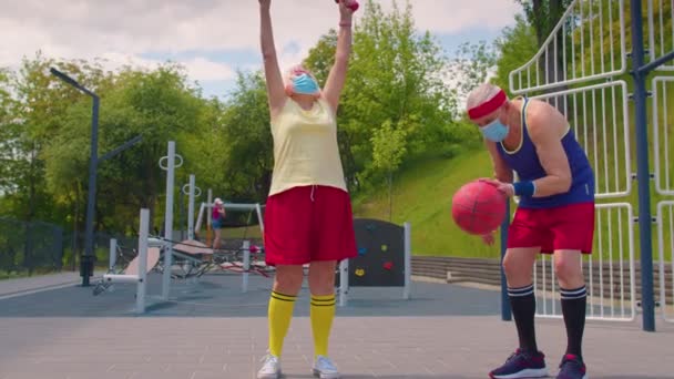 Mulher idosa ativa jogando basquete no campo de jogos esportivos durante a pandemia de coronavírus — Vídeo de Stock