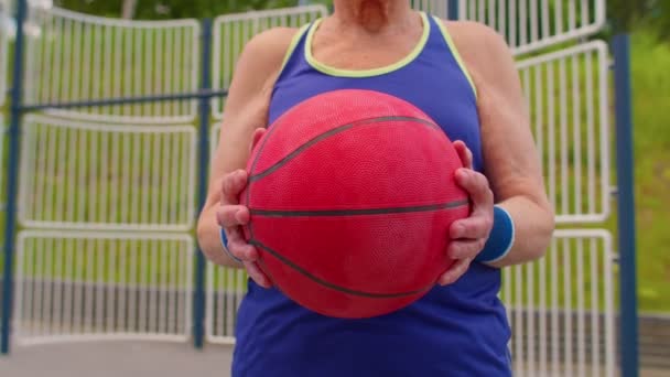 Anciano anciano abuelo atleta posando jugando con pelota al aire libre en cancha de baloncesto — Vídeo de stock
