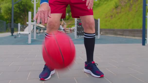 Старший старий спортсмен грає, практикуючи дриблінг з м'ячем на баскетбольному майданчику — стокове відео