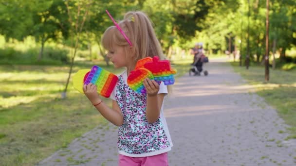 Дети девочка ребенок держа сжимая анти-стресс сенсорный экран нажмите поп это популярная игрушка в общественном парке — стоковое видео
