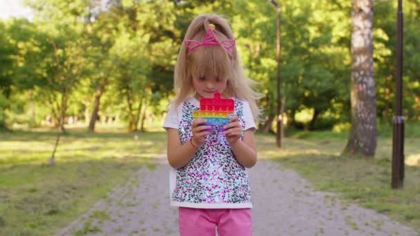 Niños niña apretando prensas colorido anti-estrés pantalla táctil empuje pop es juguete popular en el parque — Vídeo de stock