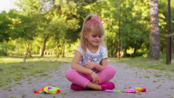 Anak gadis kecil yang sedang bermain push pop it bubble squeeze fidget sensorik mainan, stress anxiety relief game — Stok Video