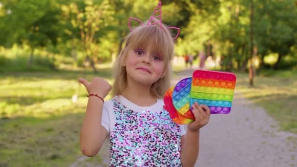 Niña sosteniendo muchas burbujas de silicona blanda de colores pop it juguetes sensoriales populares, pulgar hacia arriba — Vídeo de stock