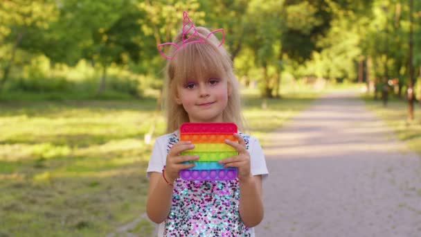 Kind Mädchen Kind spielt Quetschen Anti-Stress-Pop es Touchscreen-Spielzeug einfache Grübchen-Spiel im Park — Stockvideo