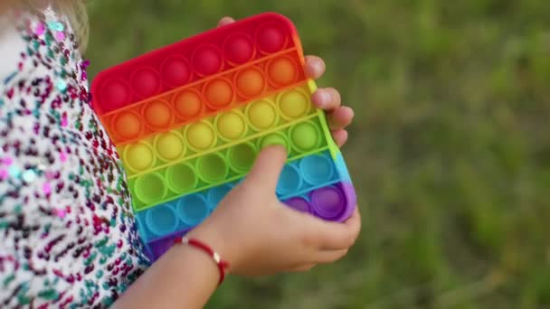 Kind meisje spelen kleurrijke squishy siliconen bubbels zintuiglijk speelgoed eenvoudige kuiltje pop it game, close-up — Stockvideo