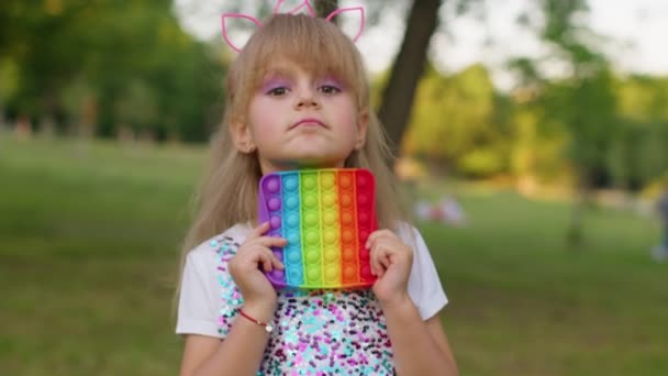 Child kid play with pop it sensory toy, girl presses on squishy silicone touch screen bubbles — Stock Video