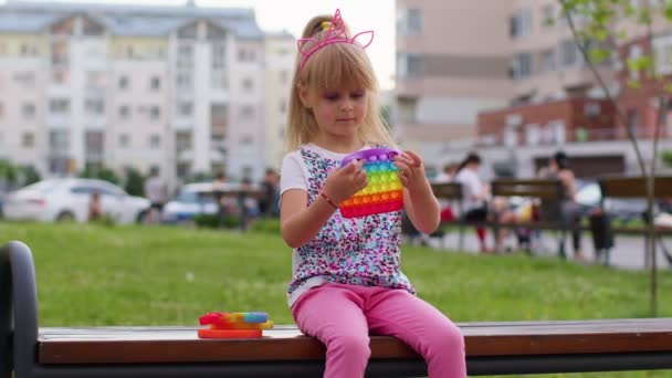 Ребенок девочка играет сжимая антистрессовые силиконовые игрушки простая ямочка поп-игры на детской площадке — стоковое видео