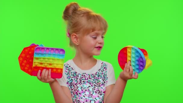 여러 가지 색깔의 끈적끈적 한 실리콘 거품 감각 장난감을 들고 있는 아이가 팝콘을 연주하는 모습 — 비디오