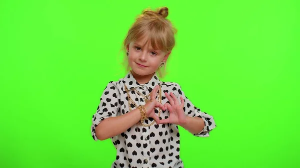 Sonriente niña hace gesto del corazón demuestra signo de amor expresa buenos sentimientos y simpatía — Foto de Stock