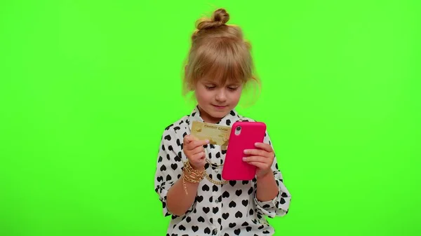 Kleine tiener kind meisje met behulp van credit bank kaart en smartphone tijdens de aankoop van online winkelen — Stockfoto