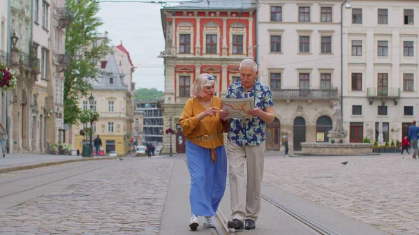 Senioren stijlvol paar toeristen man, vrouw, grootmoeder, grootvader op zoek naar een manier met behulp van papieren kaart — Stockfoto