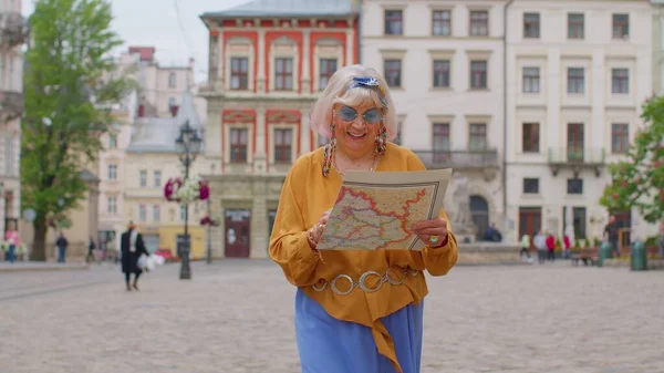 Senior elegante turista nonna donna a piedi lungo la strada, alla ricerca di modo utilizzando la mappa cartacea in città — Foto Stock