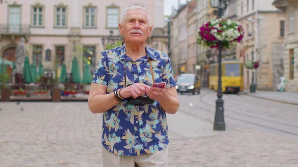 Idős elegáns turista keres utat találni okostelefon segítségével Óváros Lviv, Ukrajna — Stock Fotó