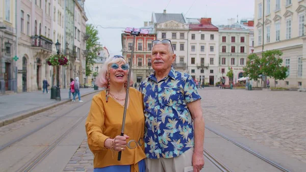 Idős idős turisták férfi nő sétál a városban okostelefon szelfi bot és fotózás — Stock Fotó