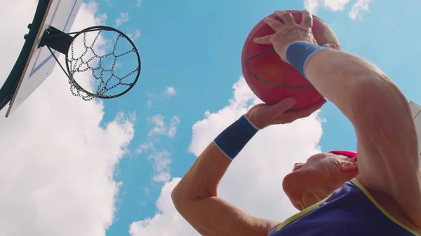 Vista hacia arriba del hombre de jugador senior enfocado jugando al juego de baloncesto, golpea con éxito en el anillo de cesta — Foto de Stock