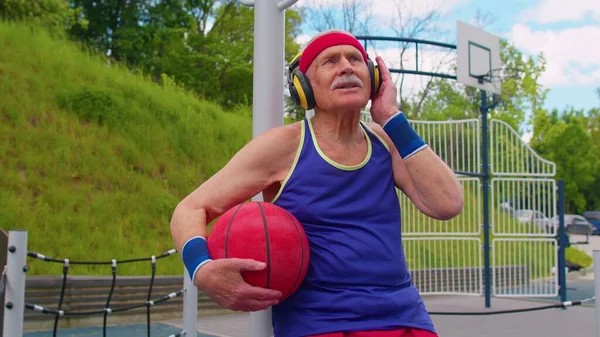 Hombre mayor abuelo después de entrenamiento de baloncesto deportivo sentado, escuchando música en el patio del patio — Foto de Stock