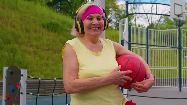 Femme âgée grand-mère après l'entraînement de basketball sportif assis écouter de la musique sur le terrain de jeu — Photo