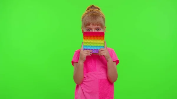 Pequeña niña apretando prensas colorido anti-estrés pantalla táctil empuje pop es juguete popular — Foto de Stock