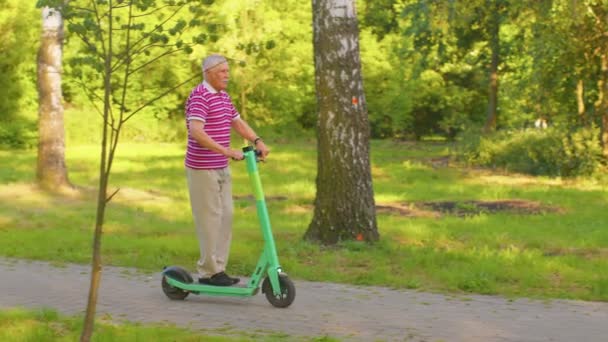 Senior stijlvolle man grootvader paardrijden elektrische scooter in het park, moderne opa rijden stedelijke voertuig — Stockvideo