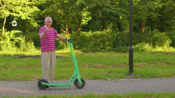 Hombre mayor elegante abuelo montar scooter eléctrico en el parque, el abuelo moderno conducir vehículo urbano — Vídeo de stock