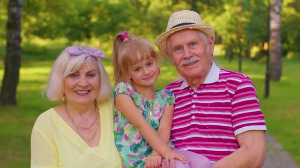 Маленькая внучка вместе со старшей бабушкой и дедушкой в парке, семейные отношения — стоковое видео